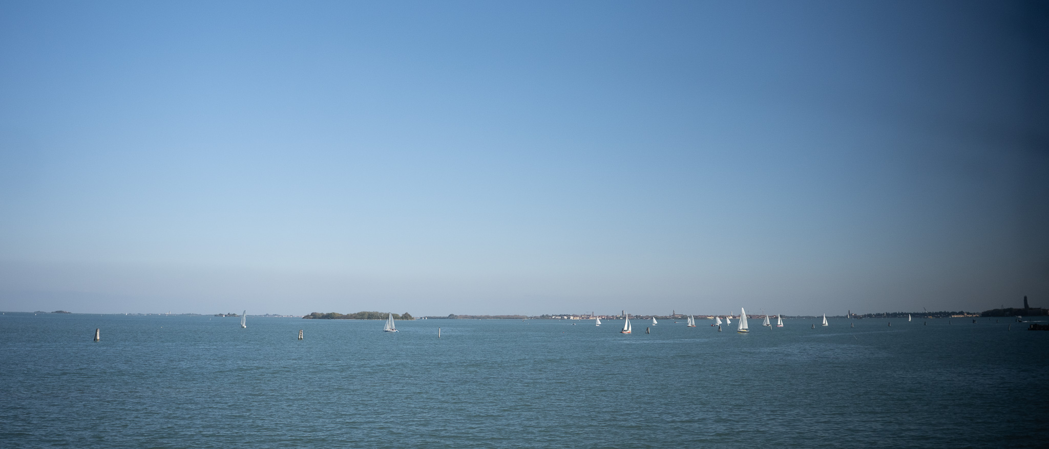 車窓からの眺め 遠くにいくつもヨットが出ている